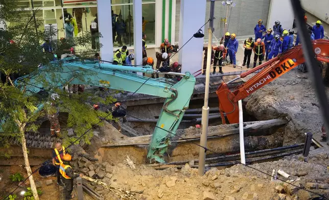 Fire and Rescue department use crane to dig a deep sinkhole after receiving reports that a woman has fallen into the sinkhole after a section of the sidewalk caved in Kuala Lumpur, Friday, Aug. 23, 2024. (AP Photo/Vincent Thian)