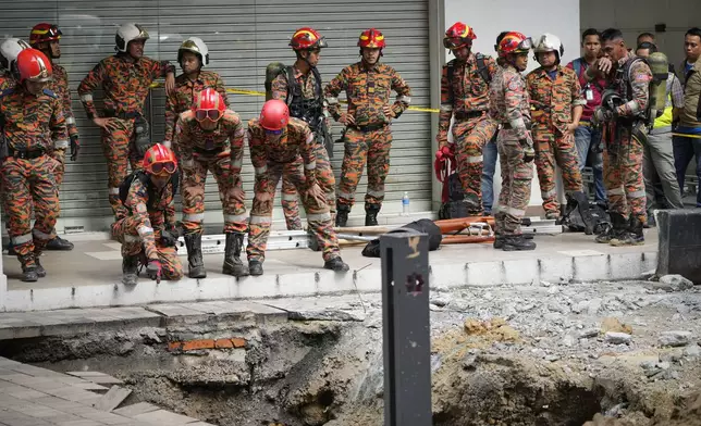 Fire and Rescue department checking on after receiving reports that a woman has fallen into the sinkhole after a section of the sidewalk caved in Kuala Lumpur, Friday, Aug. 23, 2024. (AP Photo/Vincent Thian)