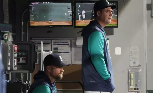 FILE - Seattle Mariners' Dan Wilson, right, stands in the dugout with acting third-base coach Tony Arnerich, left, during a baseball game against the Texas Rangers, Thursday, April 21, 2022, in Seattle. (AP Photo/Ted S. Warren, File)