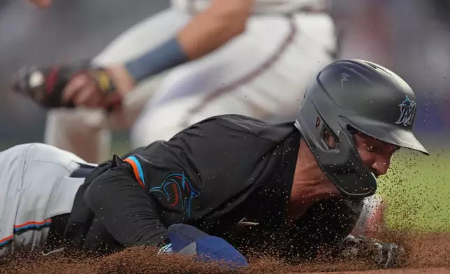 Miami Marlins' Forrest Wall is safe at third base on a throwing error by Atlanta Braves pitcher Charlie Morton in the fifth inning of a baseball game, Thursday, Aug. 1, 2024, in Atlanta. (AP Photo/John Bazemore)