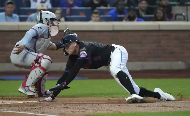 New York Mets' Brandon Nimmo, right, slides past Miami Marlins catcher Ali Sánchez, left, to score on a single hit by J.D. Martinez during the first inning of a baseball game, Friday, Aug. 16, 2024, in New York. (AP Photo/Pamela Smith)