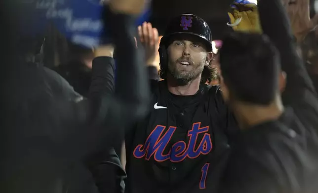 New York Mets' Jeff McNeil celebrates in the dugout with teammates after hitting a two-run home run leading to Francisco Alvarez scoring during the fourth inning of a baseball game against the Miami Marlins, Friday, Aug. 16, 2024, in New York. (AP Photo/Pamela Smith)