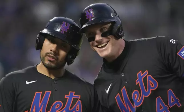 New York Mets' Harrison Bader, right, bumps helmets with a ball boy at first base after being walked by Miami Marlins pitcher Roddery Muñoz during the second inning of a baseball game, Friday, Aug. 16, 2024, in New York. (AP Photo/Pamela Smith)