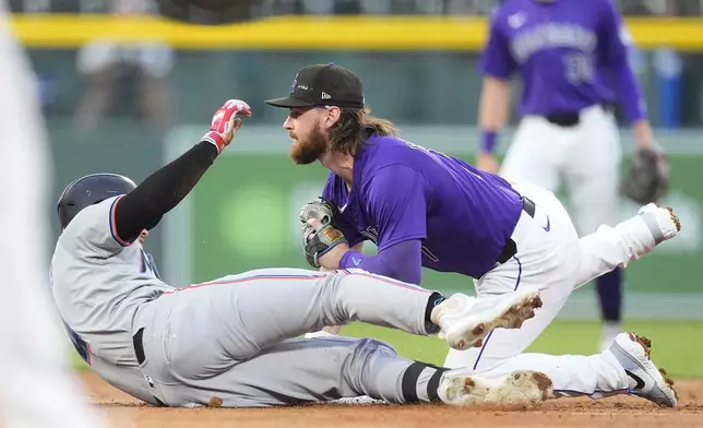 Colorado Rockies second baseman Brendan Rodgers, front right, tags out Miami Marlins' Nick Fortes, left, at second as Fortes was trying to stretch a single into a double in the third inning of a baseball game Monday, Aug. 26, 2024, in Denver. (AP Photo/David Zalubowski)