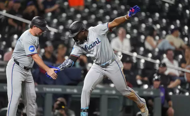 Miami Marlins third base coach Griffin Benedict, left, congratulates Jesus Sanchez as he circles the bases after hitting a three-run home run off Colorado Rockies relief pitcher Angel Chivilli in the ninth inning of after a baseball game, Tuesday, Aug. 27, 2024, in Denver. (AP Photo/David Zalubowski)