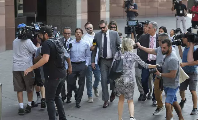 Dr. Mark Chavez, center left, a physician from San Diego, who is charged in connection with actor Matthew Perry's death from an accidental ketamine overdose, arrives with his attorney Matthew Binninger, center right, at the Roybal Federal Courthouse in Los Angeles, Friday, Aug. 30, 2024. (AP Photo/Damian Dovarganes)