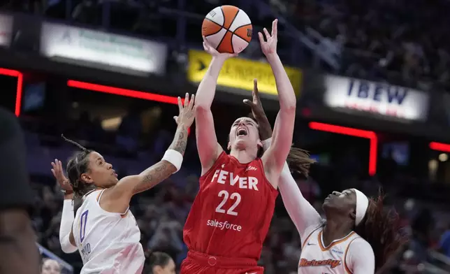 Indiana Fever guard Caitlin Clark (22) shoots against Phoenix Mercury's Natasha Cloud (0) and Kahleah Copper (2) during the second half of a WNBA basketball game, Friday, Aug. 16, 2024, in Indianapolis. (AP Photo/Darron Cummings)