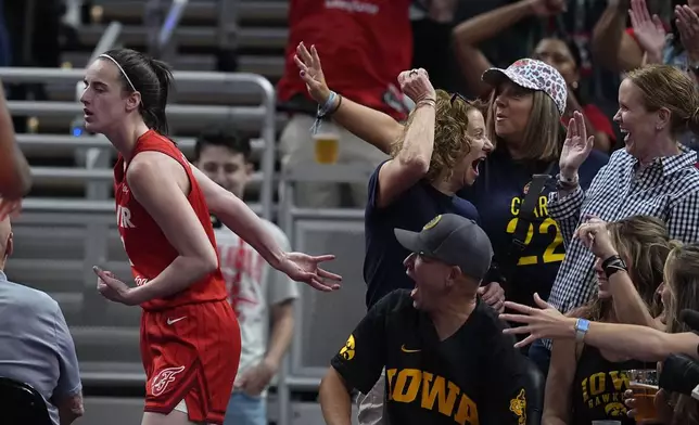 Indiana Fever guard Caitlin Clark, left, reacts with fans after hitting a shot and getting fouled during the first half of a WNBA basketball game against the Phoenix Mercury, Friday, Aug. 16, 2024, in Indianapolis. (AP Photo/Darron Cummings)