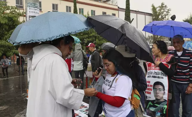 Anglican priest Rev. Arturo Carrasco gives communion to Janet Piña Montelongo during a Catholic Mass commemorating the missing of the search collective "Uniendo Esperanzas" or Uniting Hope, in Mexico City, Sunday, July 21, 2024. Piña's father Rafael went missing when he did not return home from work in 2021. (AP Photo/Ginnette Riquelme)