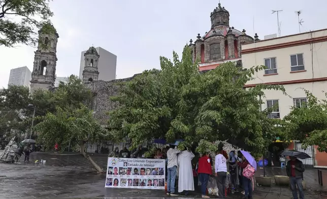 Anglican priest Rev. Arturo Carrasco stands with Benita Ornelas, in red, and her husband Marcos, as they pass out tacos after holding a Mass on the fifth anniversary of the disappearance of the couple's son Fernando Ivan Ornelas in Mexico City, Sunday, July 21, 2024. Benita and Marcos are members of the search collective "Uniendo Esperanzas" or Uniting Hope. (AP Photo/Ginnette Riquelme)