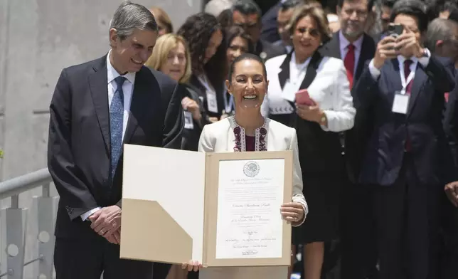 Mexican President-elect Claudia Sheinbaum, accompanied by husband Jesus Maria Tarriba, holds the official document certifying her as the winner of the presidential election as she leaves the Federal Electoral Tribunal, in Mexico City, Thursday, Aug. 15, 2024. (AP Photo/Fernando Llano)