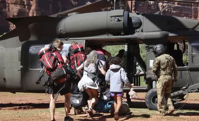 U.S. Army soldiers of the Arizona National Guard guide tourists trapped by flash flooding into a UH-60 Blackhawk, Saturday, Aug. 24, 2024, on the Havasupai Reservation in Supai, Ariz. (Maj. Erin Hannigan/U.S. Army via AP)