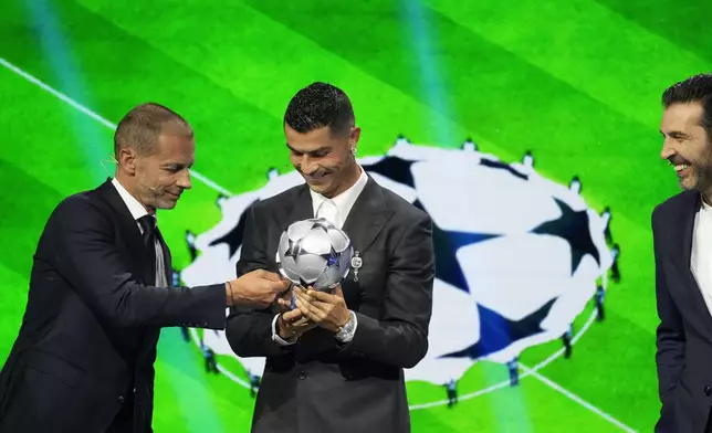 Cristiano Ronaldo, the all-time leading goalscorer in the Champions League, receives a special award from UEFA President Aleksander Ceferin in recognition of his achievements in the competition, while Former Italian goalkeeper Gianluigi Buffon looks on at right, during the Champions League, league phase, draw, in Monaco, Thursday, Aug. 29, 2024. (AP Photo/Gregorio Borgia)