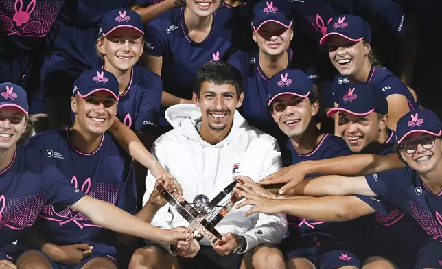 Alexei Popyrin, center bottom, of Australia, holds the winner's trophy as he poses with ball boys and girls after defeating Andrey Rublev, of Russia, in the final of the National Bank Open men's tennis tournament in Montreal, Monday, Aug. 12, 2024. (Graham Hughes/The Canadian Press via AP)