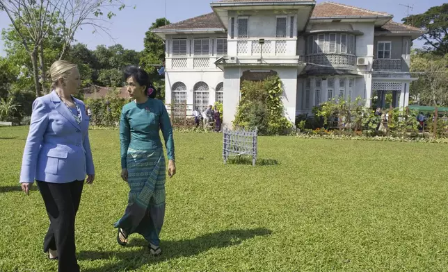 FILE - Myanmar's pro-democracy opposition leader Aung San Suu Kyi, right, and U.S. Secretary of State Hillary Rodham Clinton walk through the garden after meetings at Suu Kyi's residence in Yangon, Myanmar on Dec. 2, 2011. (AP Photo/Saul Loeb, Pool, File)