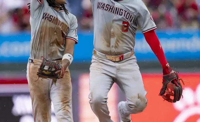 Washington Nationals shortstop C.J. Abrams, left, celebrates with second baseman Luis Garcia, right, after they won a baseball game against the Philadelphia Phillies, Sunday, Aug. 18, 2024, in Philadelphia. (AP Photo/Chris Szagola)