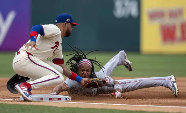 Washington Nationals' C.J. Abrams, right, steals third as Philadelphia Phillies third baseman Edmundo Sosa, left, tries to tag him during the first inning of a baseball game, Sunday, Aug. 18, 2024, in Philadelphia. (AP Photo/Chris Szagola)