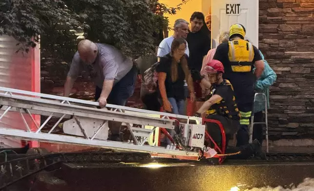 This photo provided by Beacon Hose Co. No. 1, a fire station in Beacon Falls, Connecticut, shows members of Beacon Hose Co. rescuing people from the Brookside Inn in Oxford, Conn., Sunday, Aug. 18, 2024. (Beacon Hose Co via AP)