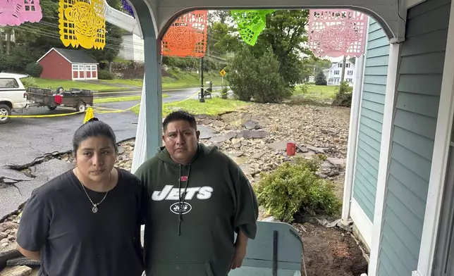 Isabel Perez and Javier Santos, owners of La Terraza Mexican Grill in Oxford, Conn., stand by their restaurant, Monday, Aug. 19, 2024, where the driveway washed away and the basement flooded when The Little River overflowed. (AP Photo/Dave Collins)