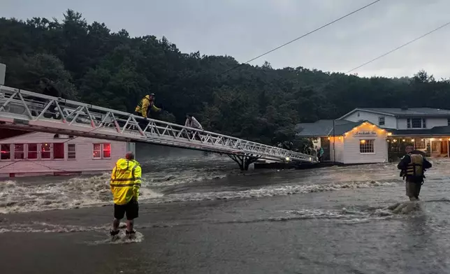 This photo provided by Beacon Hose Co. No. 1, a fire station in Beacon Falls, Connecticut, shows members of Beacon Hose Co. rescuing people from the Brookside Inn in Oxford, Conn., Sunday, Aug. 18, 2024. (Beacon Hose Co via AP)