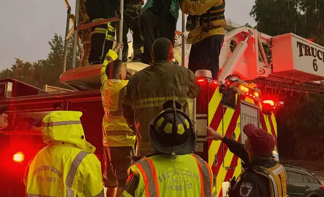 This photo provided by Beacon Hose Co. No. 1, a fire station in Beacon Falls, Connecticut, shows members of Beacon Hose Co. rescuing people from the Brookside Inn in Oxford, Conn., Sunday, Aug. 18, 2024. (Beacon Hose Co via AP)