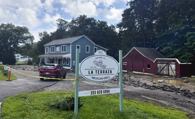 The driveway washed away and the basement flooded of Terraza Mexican Grill, owned by Isabel Perez, Javier Santos, in Oxford, Conn., when The Little River overflowed during heavy rains. (AP Photo/Dave Collins)