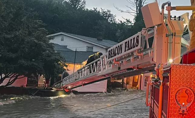 This photo provided by Beacon Hose Co. No. 1, a fire station in Beacon Falls, Connecticut, shows members of Beacon Hose Co. rescuing people from the Brookside Inn in Oxford, Conn., Sunday, Aug. 18, 2024. (Beacon Hose Co via AP)