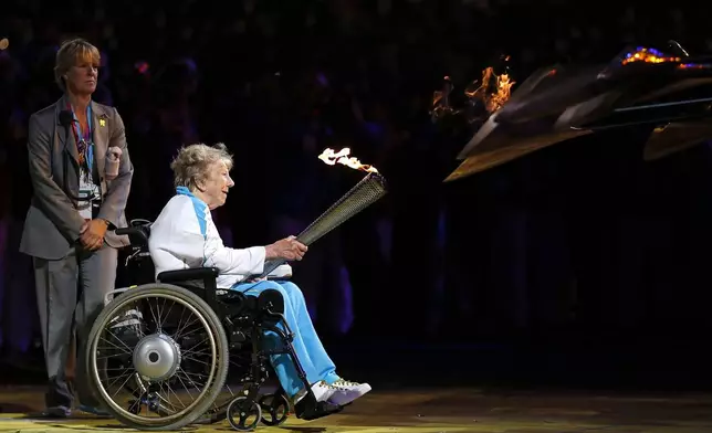 FILE - Margaret Maughan, Britain's first Paralympic gold medalist, lights the Paralympic flame during the Opening Ceremony for the 2012 Paralympics in London, on Aug. 29, 2012. The flame will be lit on Saturday Aug. 24, 2024 in Stoke Mandeville, a village northwest of London and will then travel to France under the English Channel to begin the four-day relay from northern beaches to Paris. (AP Photo/Matt Dunham, File)