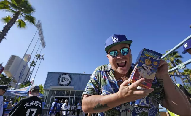 A fan mugs for the camera after getting a bobblehead of Los Angeles Dodgers' Shohei Ohtani prior to a baseball game between the Dodgers and the Baltimore Orioles Thursday, Aug. 29, 2024, in Los Angeles. (AP Photo/Mark J. Terrill)