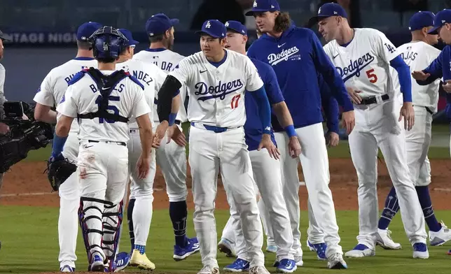 Los Angeles Dodgers' Shohei Ohtani, center, congratulates teammates after the Dodgers defeated the Baltimore Orioles 6-3 in a baseball game Thursday, Aug. 29, 2024, in Los Angeles. (AP Photo/Mark J. Terrill)