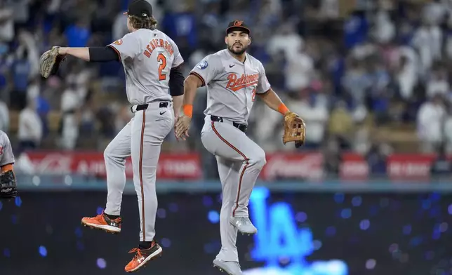 Baltimore Orioles' Anthony Santander, right, and Gunnar Henderson (2) celebrate after a win over the Los Angeles Dodgers in a baseball game, Tuesday, Aug. 27, 2024, in Los Angeles. (AP Photo/Marcio Jose Sanchez)