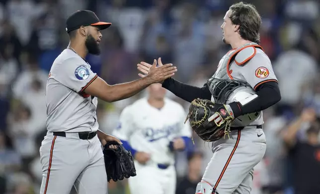 Baltimore Orioles relief pitcher Seranthony Domínguez celebrates with catcher Adley Rutschman after the last out of a baseball game against the Los Angeles Dodgers, Tuesday, Aug. 27, 2024, in Los Angeles. (AP Photo/Marcio Jose Sanchez)