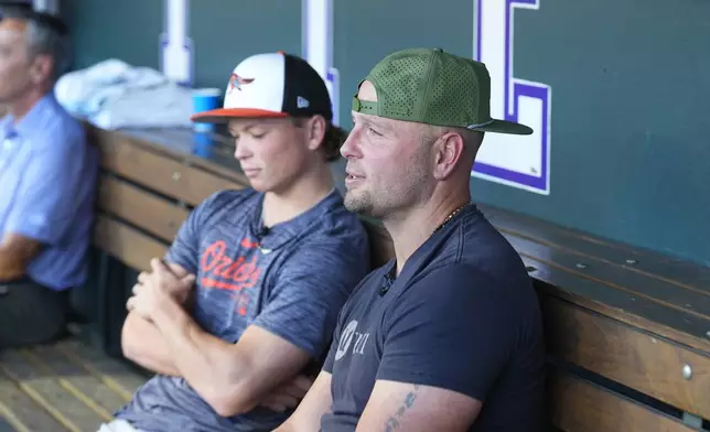 Retired Major League Baseball player Matt Holliday, front, talks to reporters with his son, Jackson, second baseman for the Baltimore Orioles, before the Orioles face the Colorado Rockies in a baseball game Friday, Aug. 30, 2024, in Denver. (AP Photo/David Zalubowski)