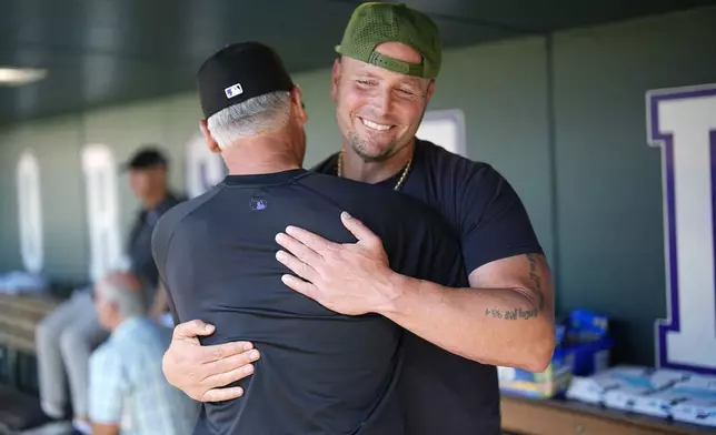 Retired Major League Baseball player Matt Holliday greets Colorado Rockies manager Bud Black before the Baltimore Orioles face the Rockies in a baseball game, Friday, Aug. 30, 2024, in Denver. (AP Photo/David Zalubowski)