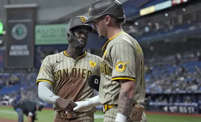 San Diego Padres' Jurickson Profar, left, celebrates with on-deck batter Jackson Merrill after scoring on an RBI single by Manny Machado off Tampa Bay Rays starting pitcher Taj Bradley during the first inning of a baseball game Friday, Aug. 30, 2024, in St. Petersburg, Fla. (AP Photo/Chris O'Meara)