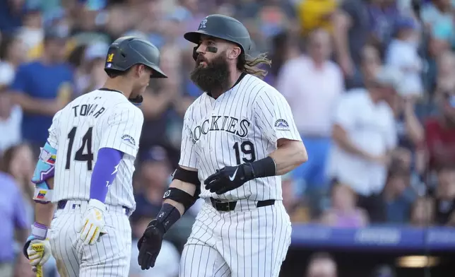 Colorado Rockies' Ezequiel Tovar, left, congratulates Charlie Blackmon, right, who crosses home plate after hitting a two-run home run off San Diego Padres pitcher Matt Waldron in the second inning of a baseball game Friday, Aug. 16, 2024, in Denver. (AP Photo/David Zalubowski)