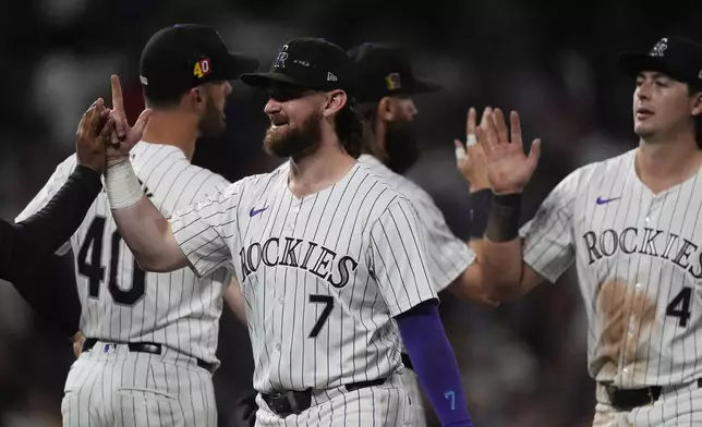 Colorado Rockies second baseman Brendan Rodgers (7) is congratulated after a baseball game against the San Diego Padres, Friday, Aug. 16, 2024, in Denver. (AP Photo/David Zalubowski)