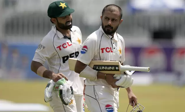 Pakistan's Saud Shakeel, right, and Mohammad Rizwan walk off the field on the lunch break during the second day of first cricket test match between Pakistan and Bangladesh, in Rawalpindi, Pakistan, Thursday, Aug. 22, 2024. (AP Photo/Anjum Naveed)