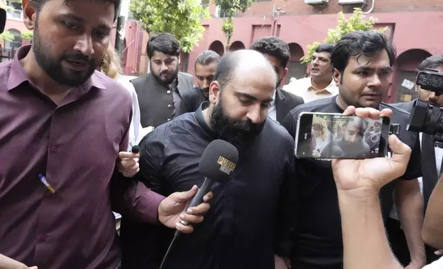 Members of media chase Farhan Asif, center, a freelance web developer who was arrested and charged with cyber terrorism for his alleged role in spreading misinformation that led to widespread rioting in the U.K. earlier this month, as he leaves with officials after his court appearance, in Lahore, Pakistan, Monday, Aug. 26, 2024. (AP Photo/K.M. Chaudary)