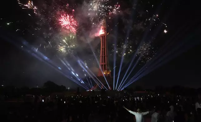 People watch fireworks light the sky close to the Minar-e-Pakistan or Pakistan monument during the Pakistan Independence Day celebrations, in Lahore, Pakistan, Wednesday, Aug. 14, 2024. (AP Photo/K.M. Chaudary)