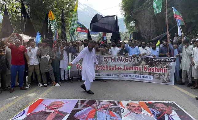 Supporters of Pasban-e-Hurriyat Jammu Kashmir pour fuel to burn the portraits of Indian Prime Minister Narendra Modi, and other officials during a protest to show solidarity with the Kashmiri people on the eve of the fifth anniversary of India's decision to strip the disputed region of its semi-autonomy, in Muzaffarabad, Pakistan, Monday, Aug. 5, 2024. (AP Photo/M.D. Mughal)