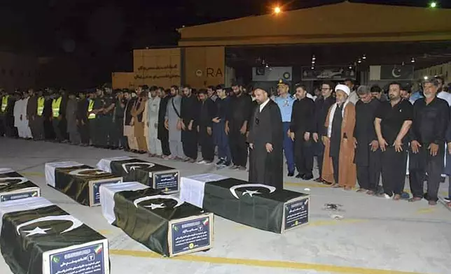 In this photo released by the Pakistan Air Force, officials offer funeral prayer of Shiite Muslim pilgrims who were killed in a bus crash in Iran while heading to Iraq for a pilgrimage, after their bodies arrived at an airbase in Jacobabad, Pakistan, Saturday, Aug. 24, 2024. (Pakistan Air Force via AP)