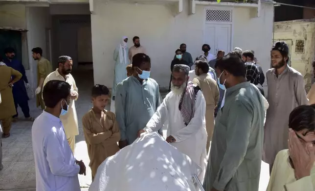 Relatives stand around a body of a passenger, who was killed by gunmen at a highway in Musakhail, and wait for transportation at a hospital, in Quetta, Pakistan, Monday, Aug. 26, 2024. (AP Photo/Arshad Butt)