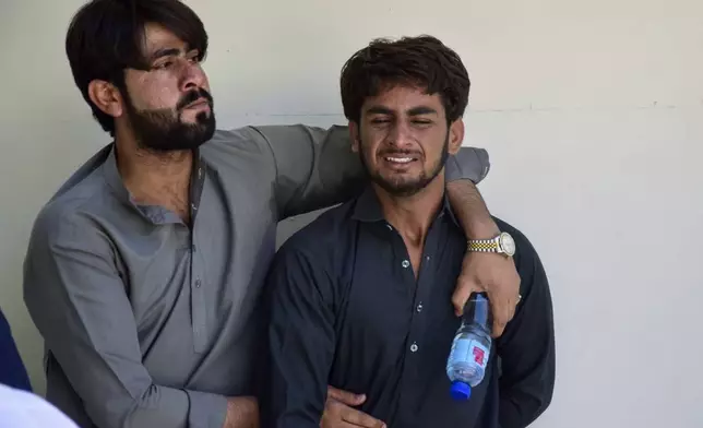 A man comforts another, who mourns over the death of his family member, killed by gunmen at a highway in Musakhail, at a hospital, in Quetta, Pakistan, Monday, Aug. 26, 2024. (AP Photo/Arshad Butt)