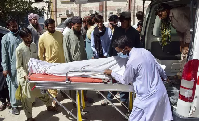 Volunteers and relatives load the body of a passenger, who was killed by gunmen at a highway in Musakhail, into an ambulance after collecting it from a hospital, in Quetta, Pakistan, Monday, Aug. 26, 2024. (AP Photo/Arshad Butt)