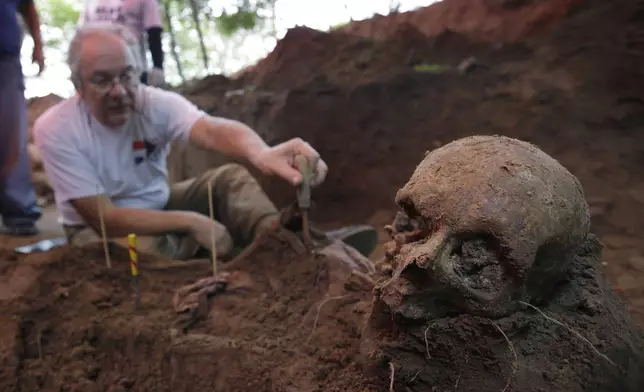 FILE - Rogelio Goiburú, member of Paraguay's Truth and Justice Commission, looks at skeletal remains found buried at the National Police Special Forces headquarters in Asuncion, Paraguay, March 19, 2013. (AP Photo/Jorge Saenz, File)