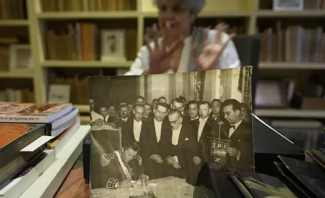 Historian Milda Rivarola shows a photograph from her private archive of Gen. Alfredo Stroessner signing a presidential oath as he enters office following his 1954 military coup, in Asuncion, Paraguay, Wednesday, Aug. 14, 2024. (AP Photo/Jorge Saenz)