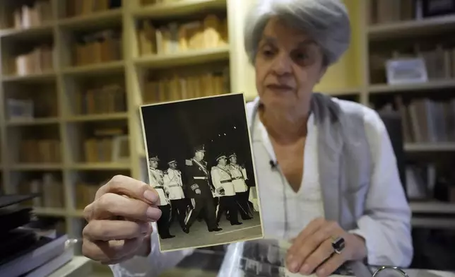 Historian Milda Rivarola holds a photograph from her private archive of Gen. Alfredo Stroessner and other military officers at a 1956 parade, in Asuncion, Paraguay, Wednesday, Aug. 14, 2024. (AP Photo/Jorge Saenz)