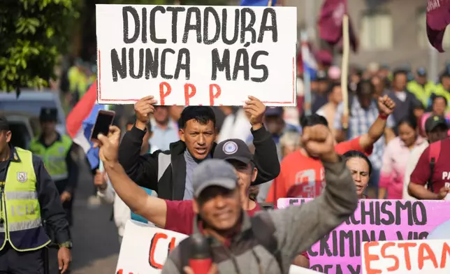 An anti-government protester holds a sign with a message that reads in Spanish; "Dictatorship never again", during an opposition rally, marking a year since President Santiago Pena's inauguration, in Asuncion, Paraguay, Thursday, Aug. 15, 2024. (AP Photo/Jorge Saenz)