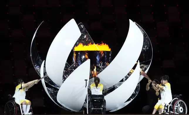 Japan's Yui Kamiji, centre, Shunsuke Uchida, right, and Karin Morisaki light the Paralympic cauldron during the opening ceremony for the 2020 Paralympics at the National Stadium in Tokyo, Aug. 24, 2021. (AP Photo/Shuji Kajiyama)